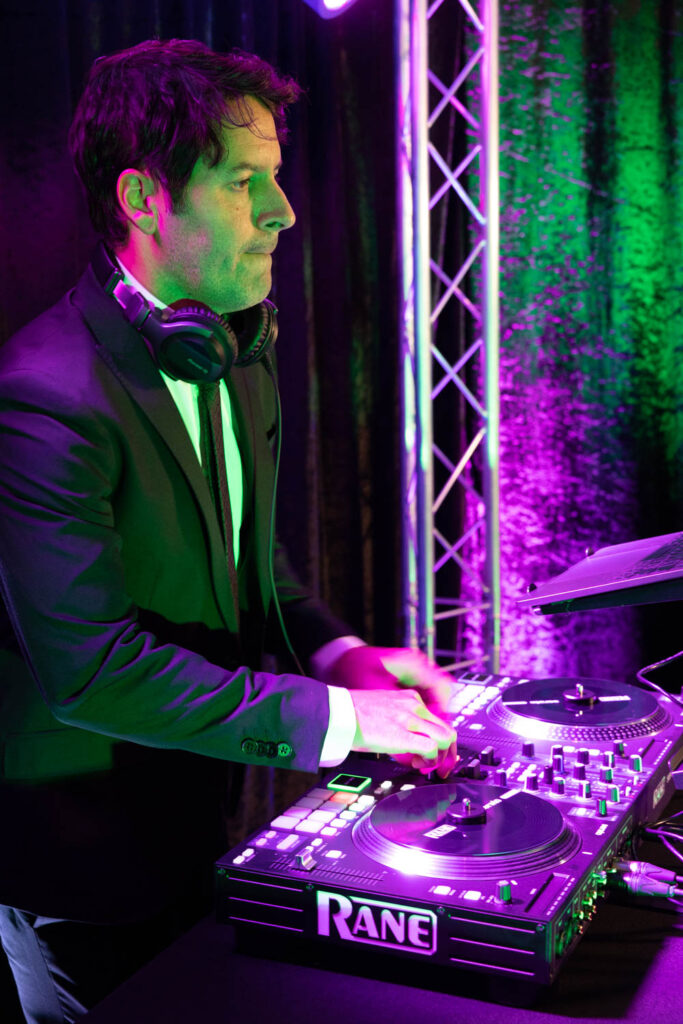 DJ Joe Taylor photographed from the side in a suit at his sound board