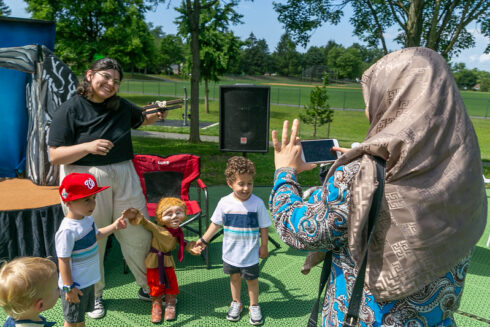 Caregiver taking a photo of children with puppets at a Puppet Co show