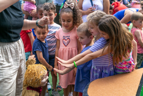 Children reaching their hands out to touch a puppet at Puppet Co show