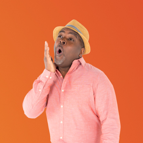 Uncle devin wearing a pink shirt and straw hat against an orange background patting his face