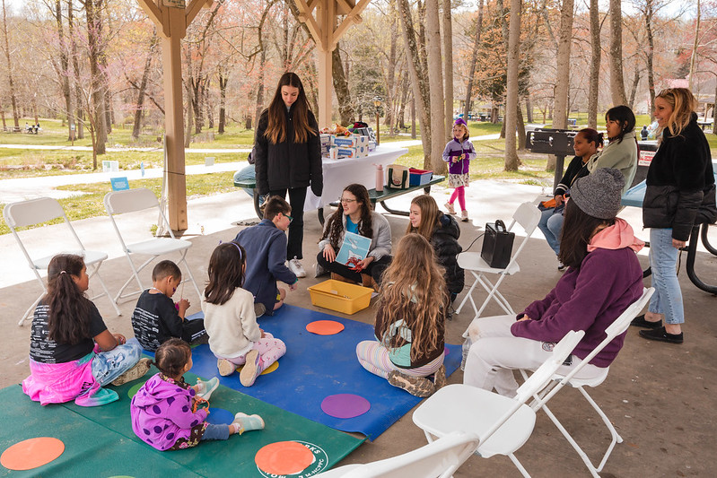 A group of children listening to an adult read a book.