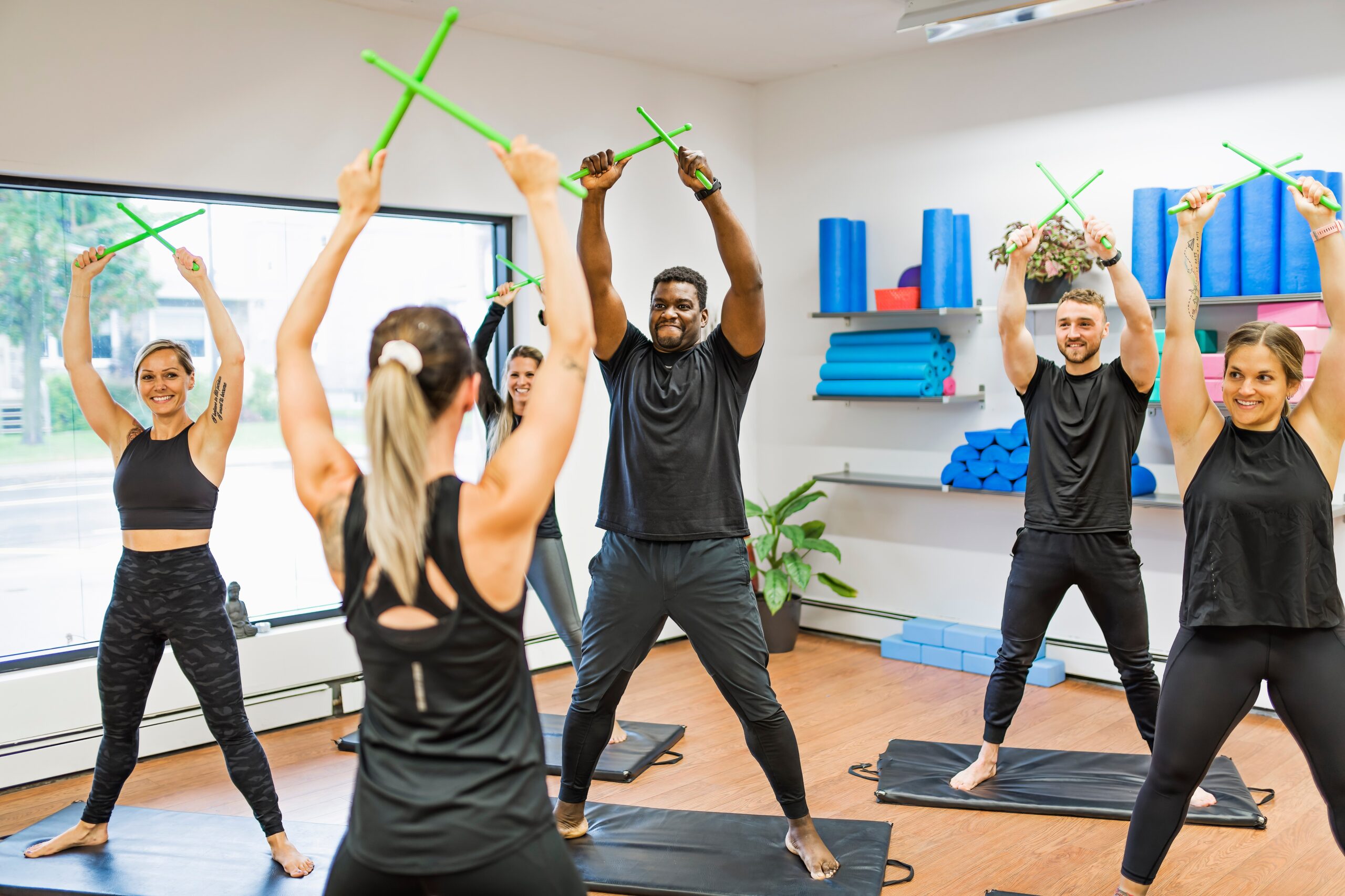 a group of people enjoying a pound fitness class with their drum sticks in the air