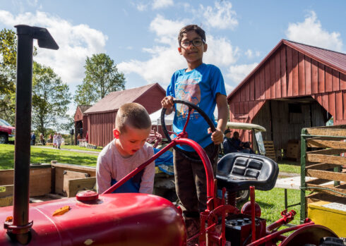 Young children playing on a tractor. 