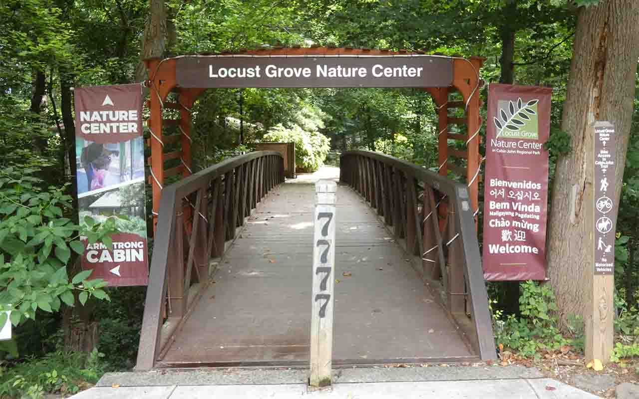 A bridge with signs for Locust Grove Nature Center and a number that says 7777