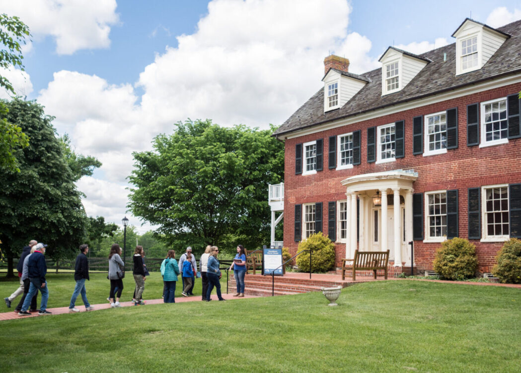 A group tour stands in front of Woodlawn Manor