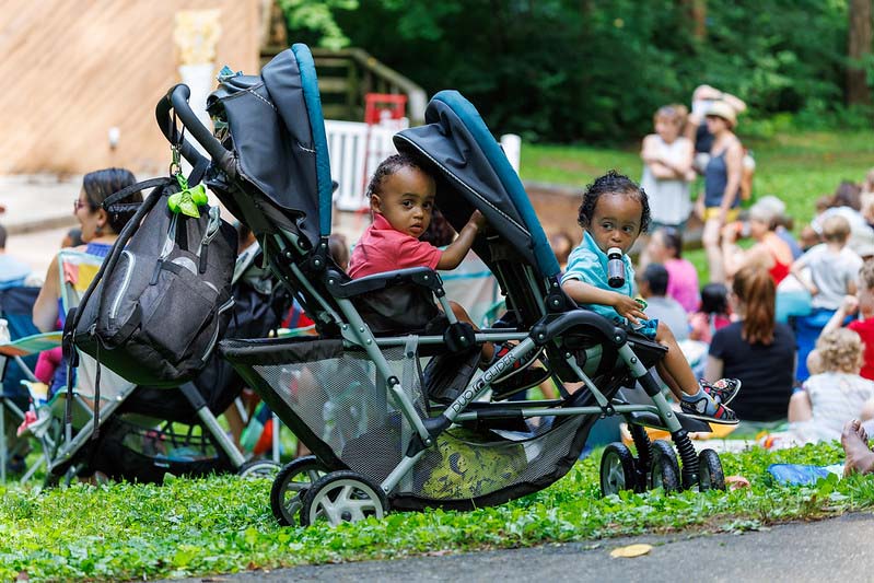 two babies in a stroller  at Happenstance Theater production in summer of 2023