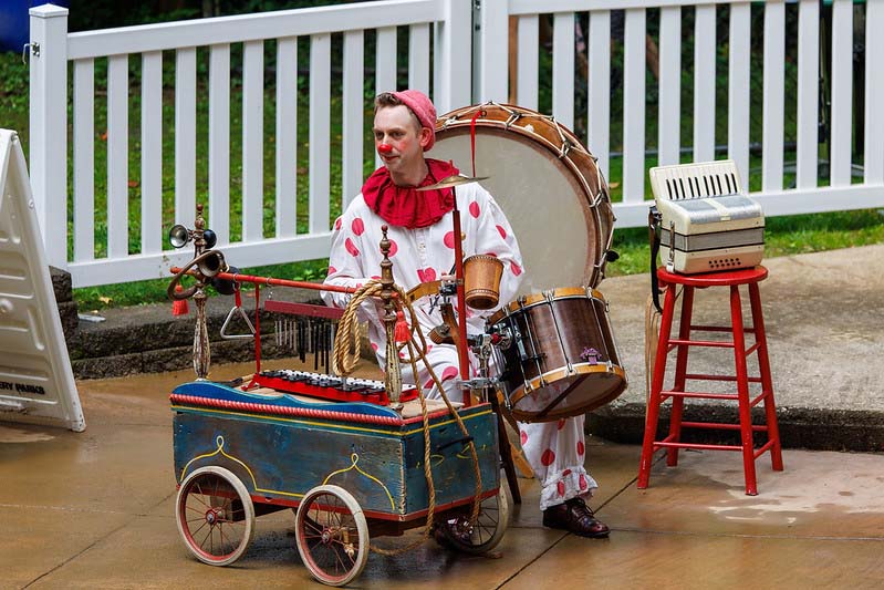 clown playing on musical instruments Happenstance Theater production in summer of 2023