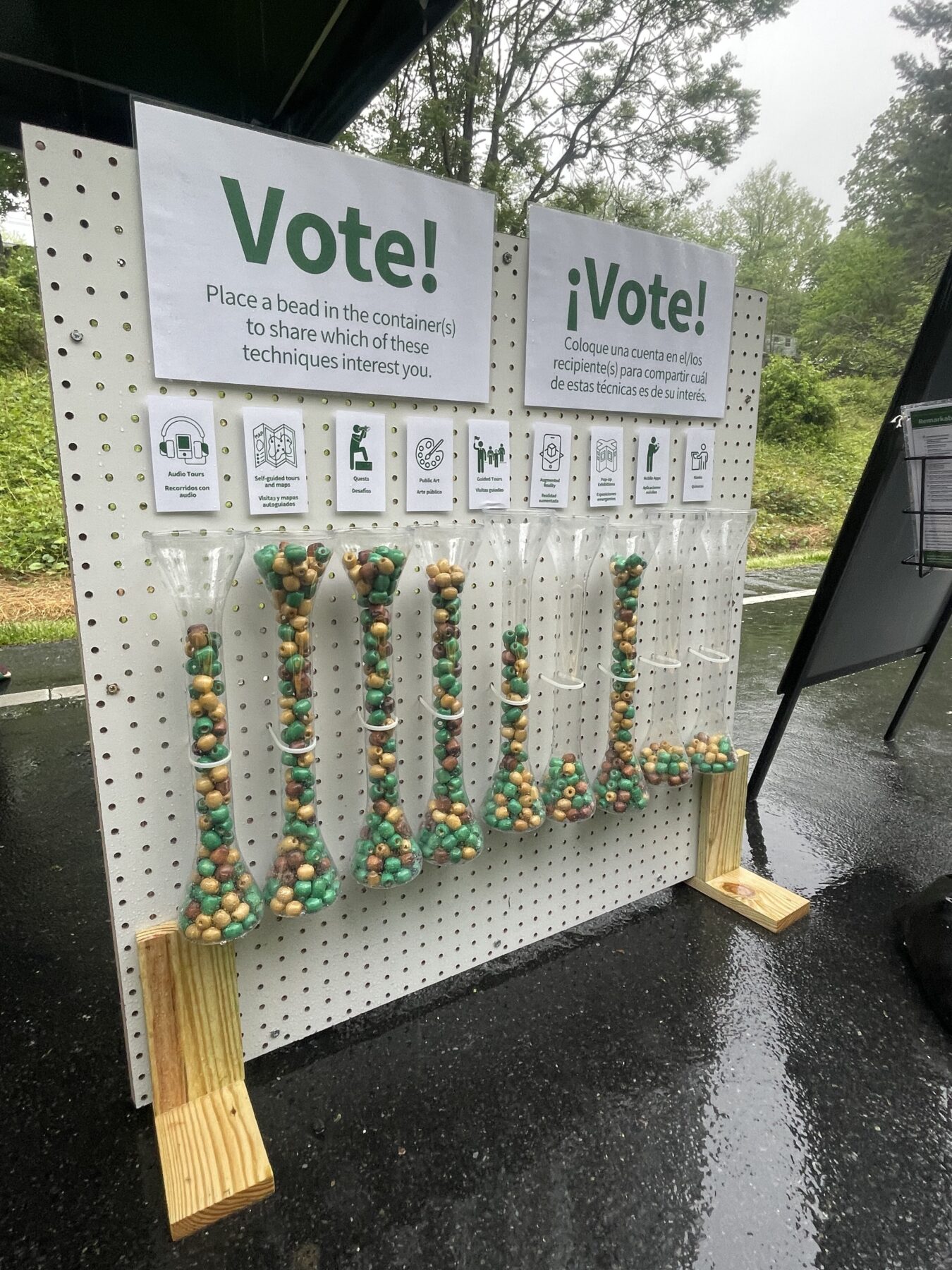 A photo showing a pegboard with clear containers filled with beads. The text above the containers reads "Vote."