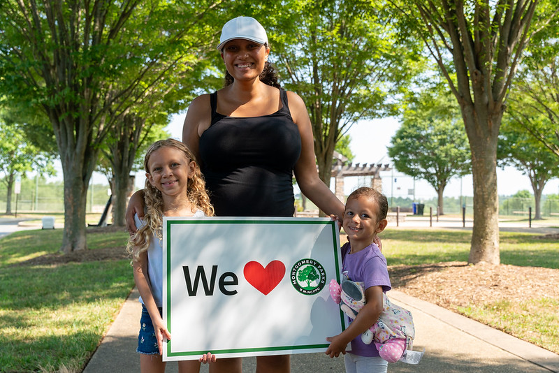 parent and children smiling and posing with sign that says "we love parks"