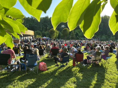 People sitting on the Brookside Gardens Visitor Center lawn enjoying the June Concert series free music performances