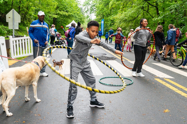 young boy hoola hooping on the parkway with other kids