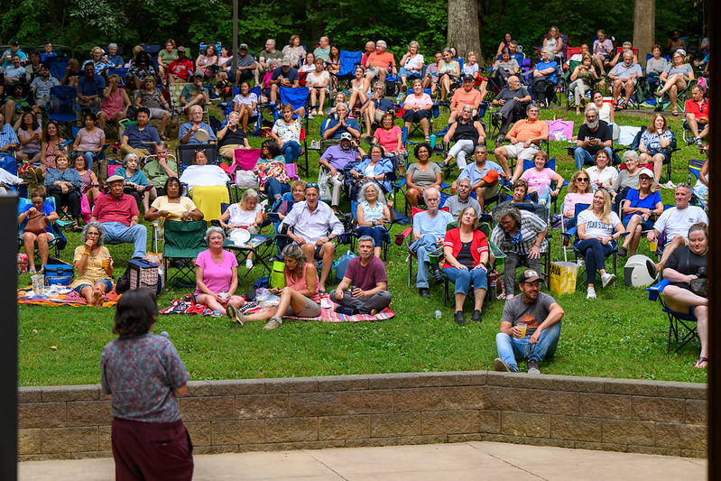 Large crowd on lawn watching comedian perform