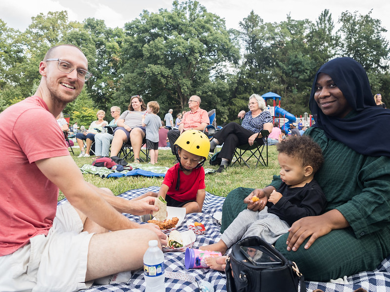 Family of 4 sits on picnic blanket smiling at camera