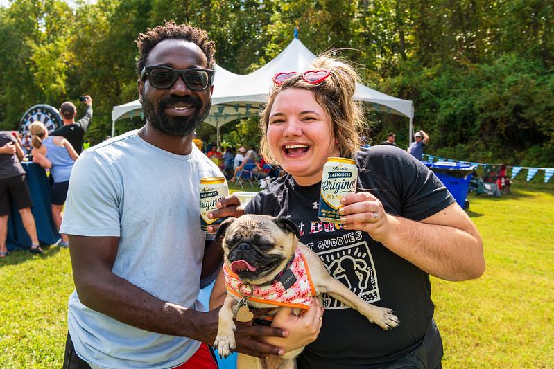 Attendees holding beers and dog smiling at Ale Trail 2024