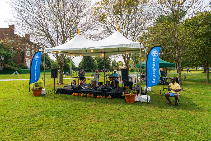 Band preforming on small stage in field at Needwood mansion