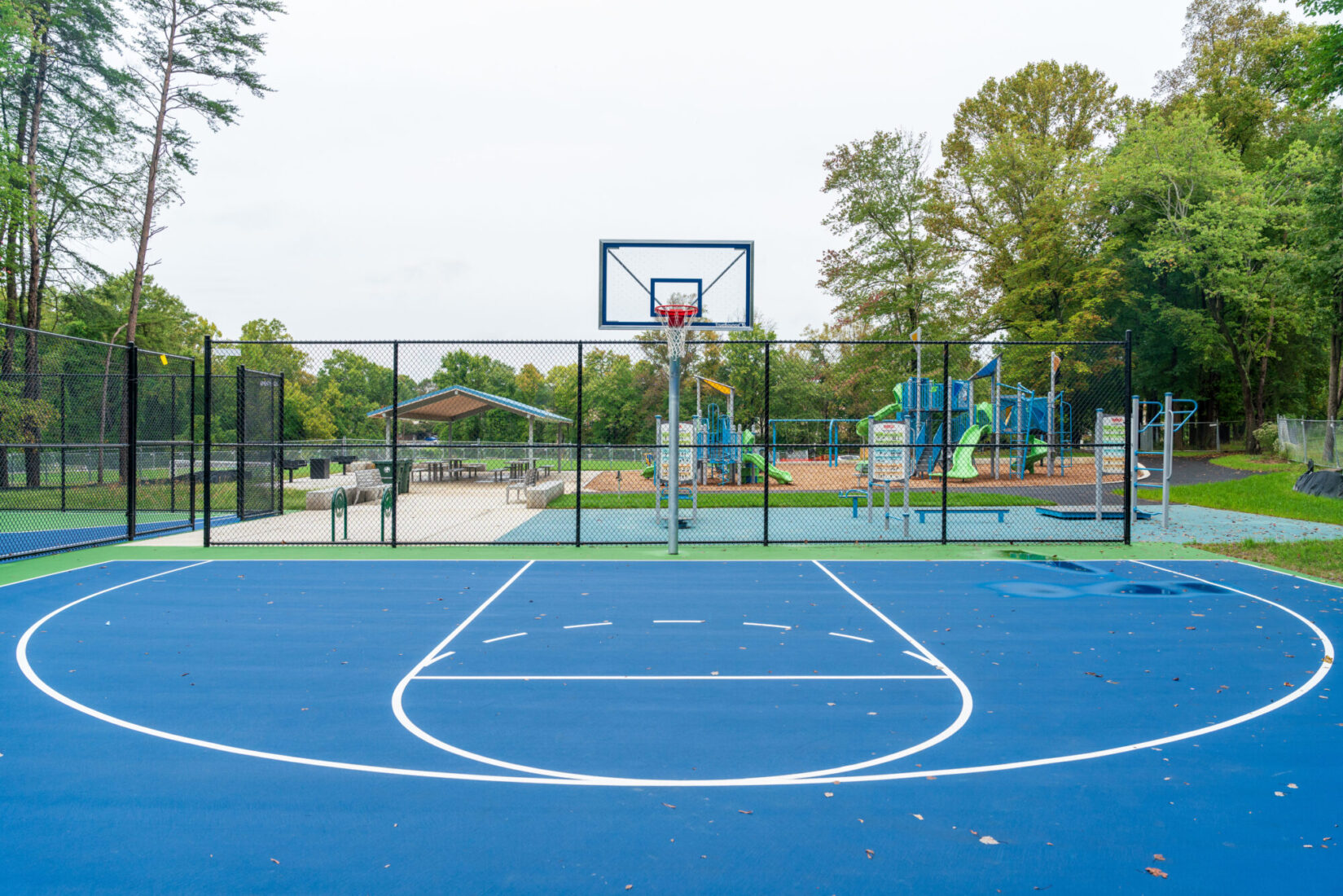 Basketball court at Strathmore Local Park with exercise equipment and playground in the background