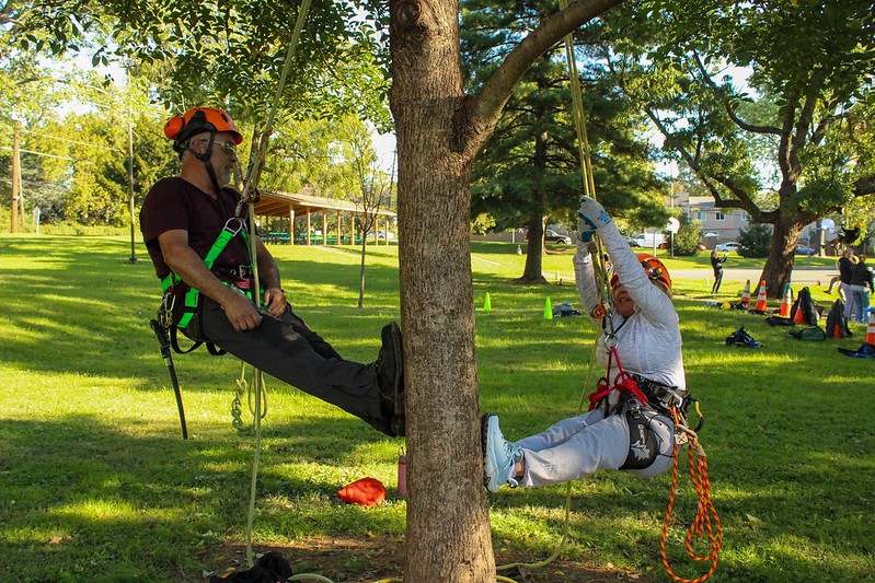 Tree crew instructor and attendee propel themselves by base of tree