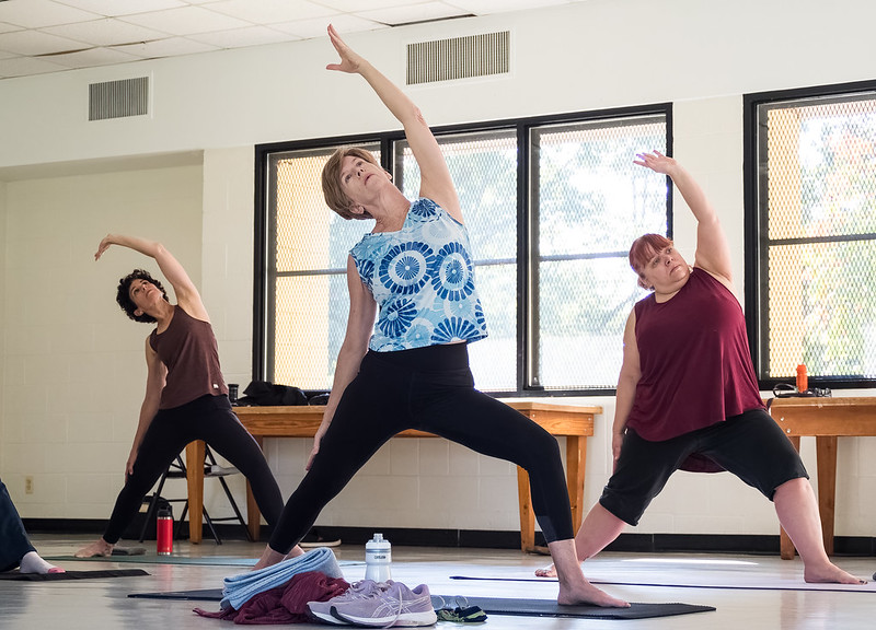 Attendees practice yoga positions reaching one hand upwards