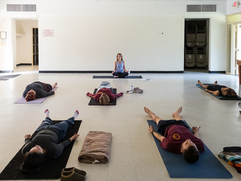 Attendees practice yoga positions while laying flat on the floor