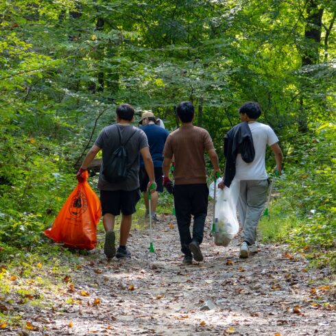 A group walking on a trail volunteering to pick up trash