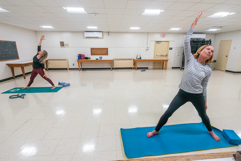 Attendee and instructor reach one arm upwards for a yoga position