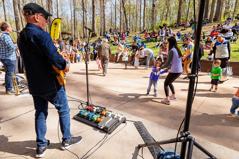 Musicians play while crowd dances and looks on from background