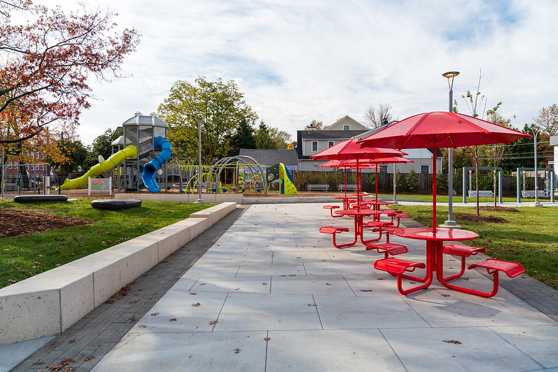 Red picnic tables and playground at Caroline Freeland Urban Park