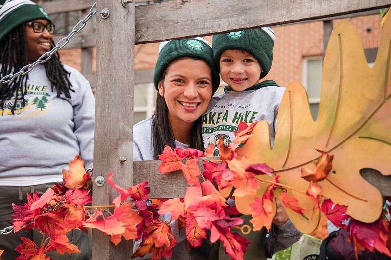 Mother and son smiling surrounded by autumn leaves.