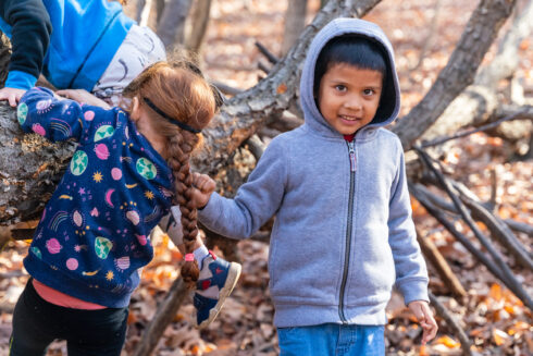 Two children play outdoors in the fall or winter.