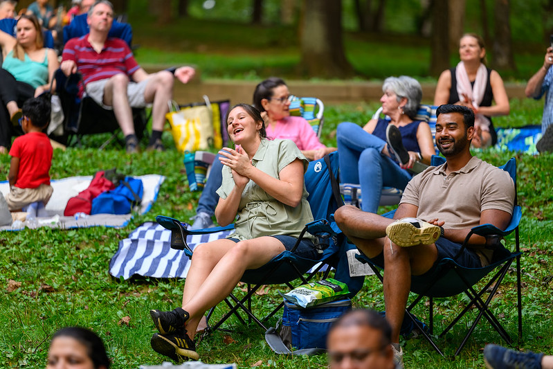 A young couple smiles while enjoying live music sitting on lawn chairs