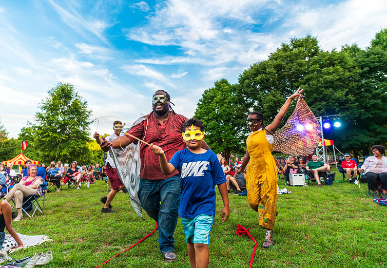 Attendees and performers dance around in masks and colorful wings