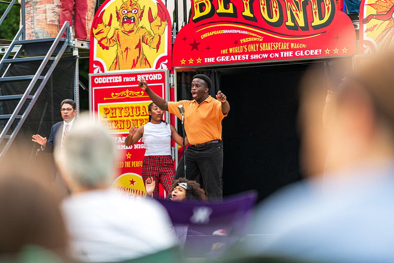 Performer sings into microphone with fellow performers singing behind