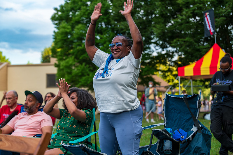 Audience member stands up and raises hands at performance