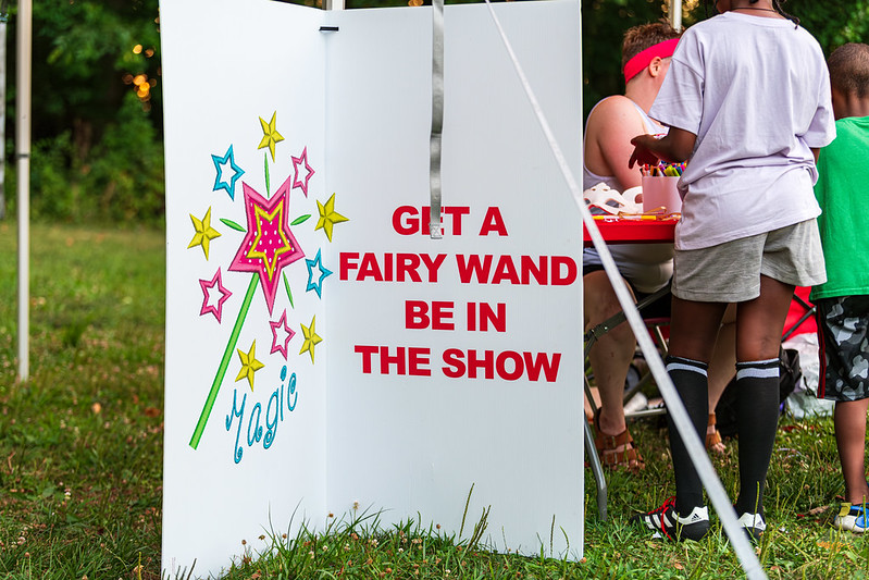 White sign that reads 'get a fairy wand, be in show' with fairy wand image on the other side