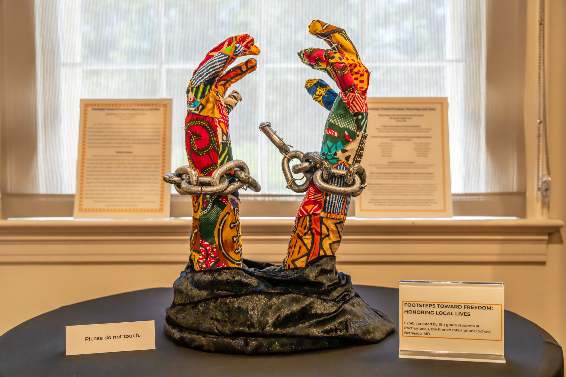 A sculpture of hands breaking chains