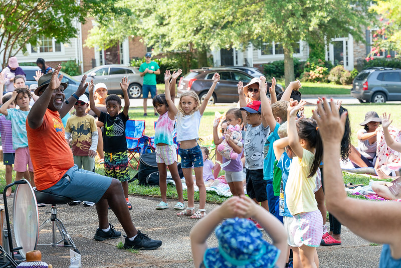 Kids raise their hands in the air with performer, Uncle Devin