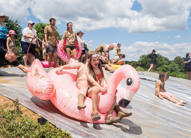 Kids ride inflatable flamingo down slide at Mudfest