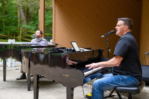 two people playing pianos on stage. dueling pianos,