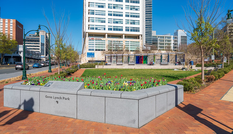 image of Gene Lynch Urban Park with newly installed art featuring a series of stainless-steel framed, glass panels with a graphic film creating a kaleidoscopic-colored effect