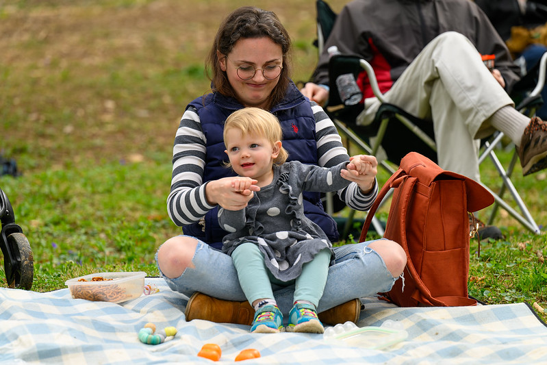 Mom holds young child as they watch from the audience