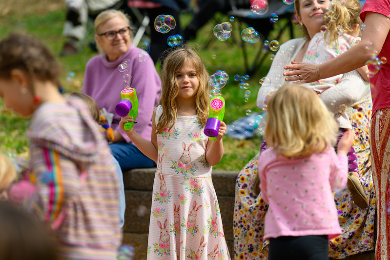 Young girl holds a bubble gun in both hands