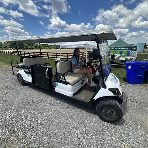 A person driving a ADA shuttle cart.