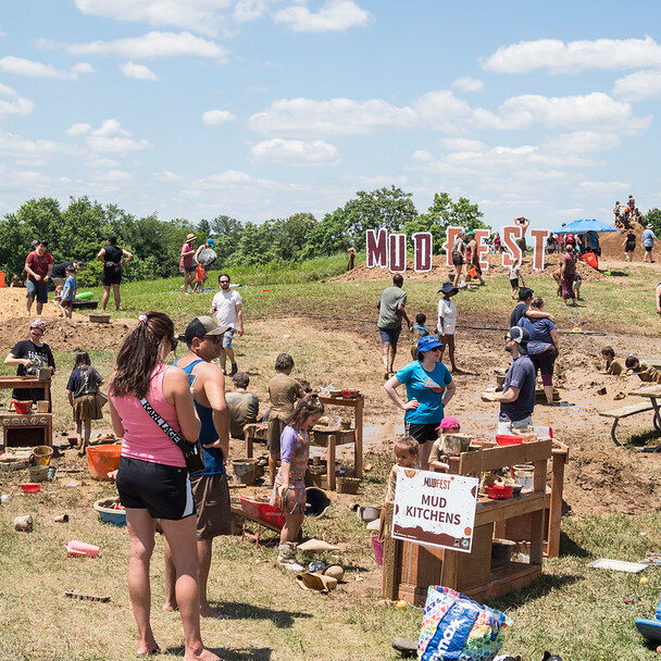 Families playing in an area marked "mud kitchen".