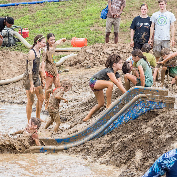Children playing in the mud using a kid slide.