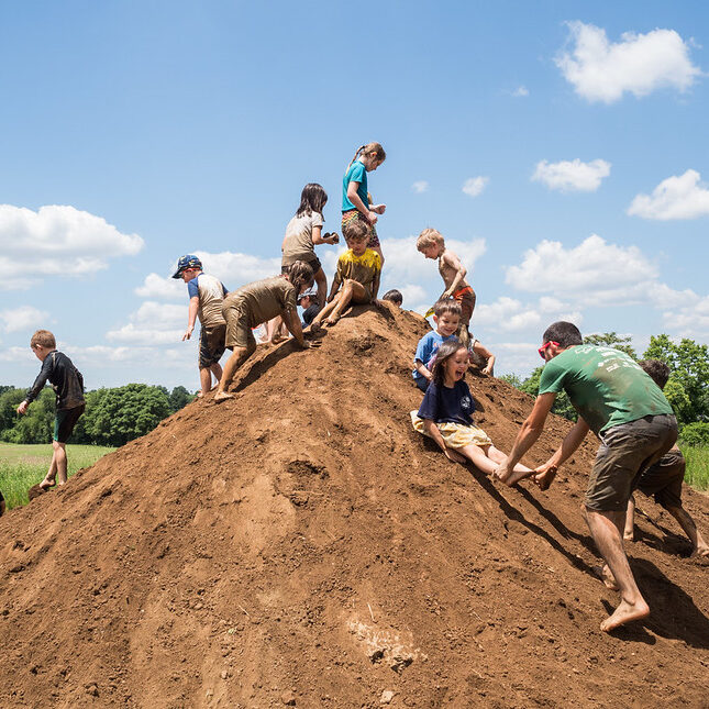 Children playing on top of a mud hill.