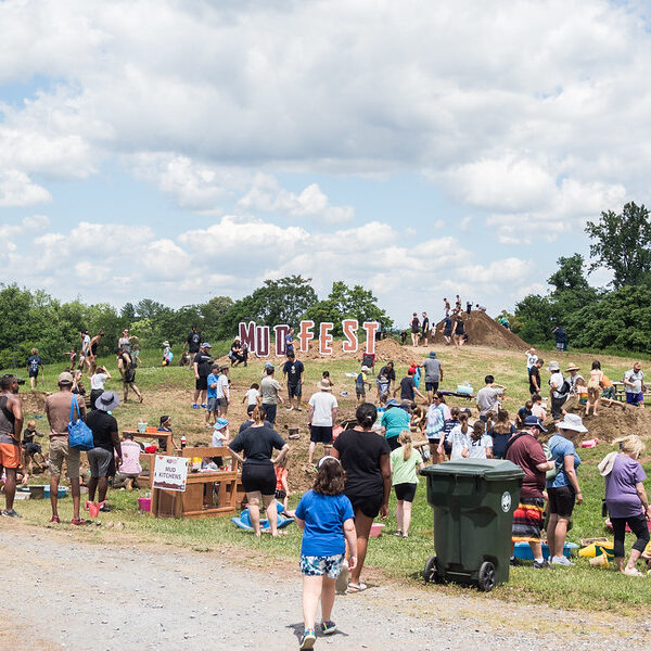 A crowd playing at MudFest and a green trash bin.