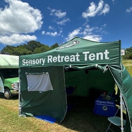 A green canopy tent with sides and an opening for a door labeled " Sensory Retreat Tent".