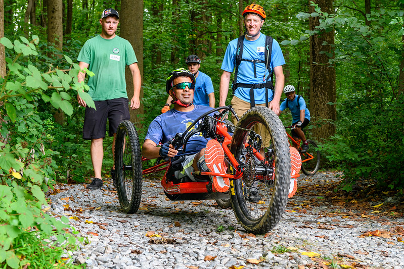 Man with sunglasses and helmet riding hand-powered recumbent mountain bike