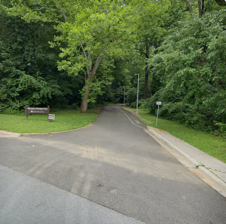 Outdoor paved path with a brown park sign.