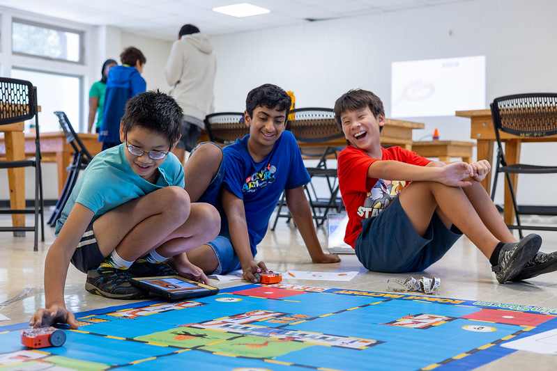 Group of pre-teens laughing and working on robots